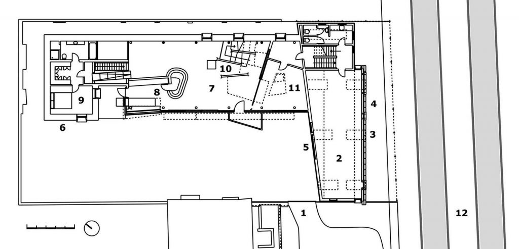 Primera planta de la Casa de Paja (2001): 1. Callejón 2. Estudio 3. Proyección de gavión 4. Fachada de sacos 5. Fachada acolchada 6. Muro de paja 7. Estar 8. Cocina con fresquera 9. Dormitorio 10. Biblioteca-torre 11. Comedor 12. Ferrocarril