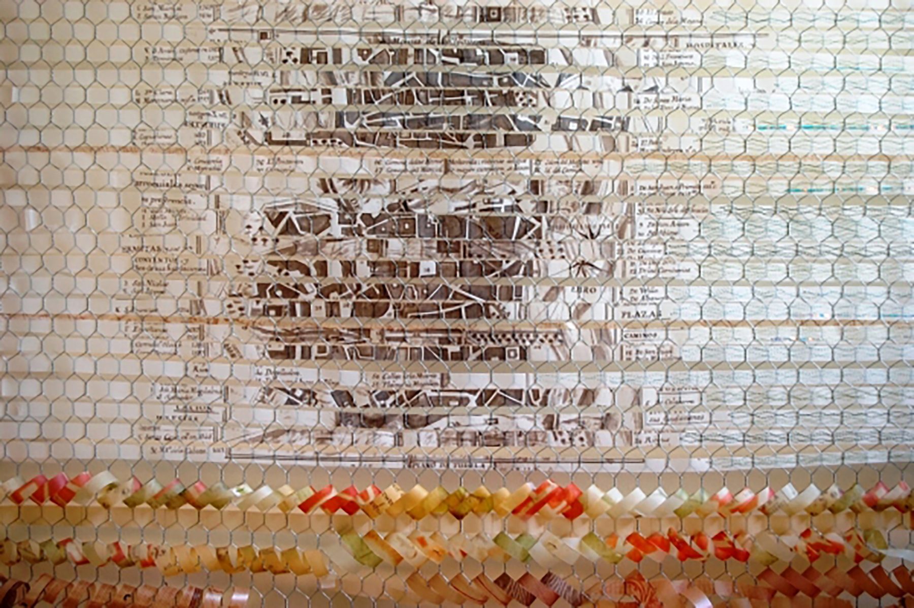 Detail of a weave of paper threads on a hexagonal mesh: fragments of a town plan printed in brown can be made out in the centre and, in the lower band, strips of red, orange and yellow paper.