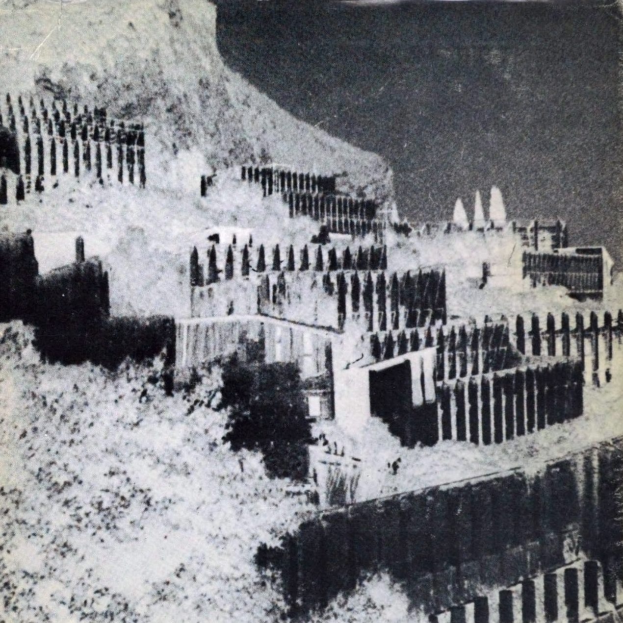 Cubierta de libro con una fotografía en blanco y negro de tonos invertidos: construcciones escalonadas en terrazas sobre una ladera, coronadas por hileras de remates apuntados, bajo un cielo oscuro.