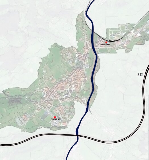 Plano de la villa de Grado sobre ortofoto, con el río en azul y la autovía A-63 al este; dos puntos rojos señalan la estación de FEVE, en el borde norte del casco, y la estación de autobuses, en el extremo sur.
